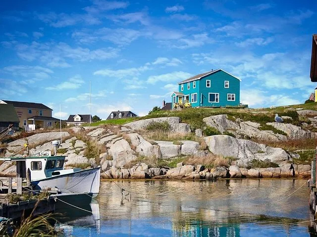 Ein blaues Haus auf einem felsigen Hügel mit Blick auf einen kleinen Hafen mit Booten.
