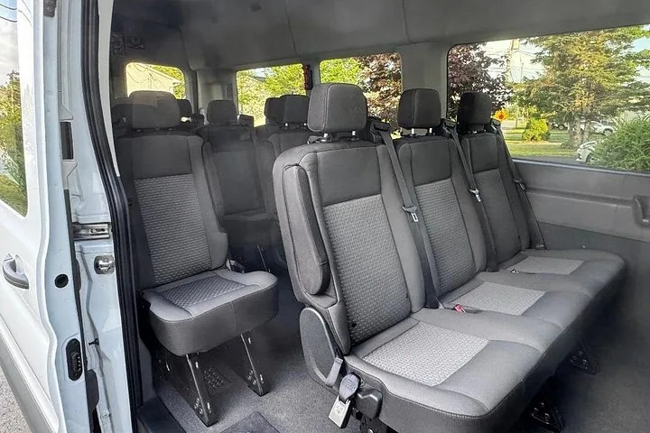 Innenansicht eines Tourvans mit Reihen leerer grauer Passagiersitze.