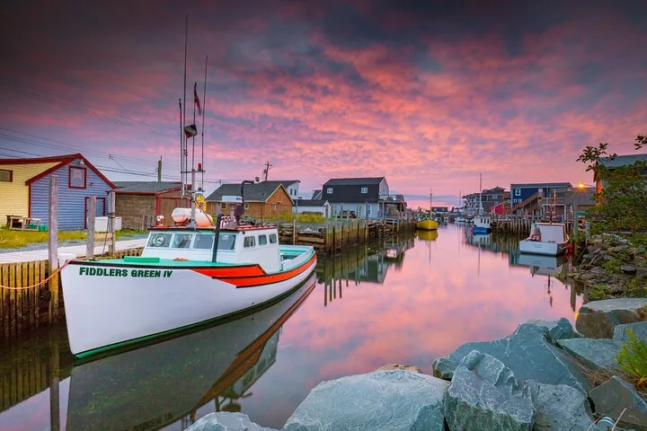 Fishing boat docked in a calm harbor at sunset with colorful sky