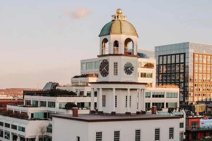 Der Town Clock von Halifax mit modernen Gebäuden im Hintergrund bei Sonnenuntergang.