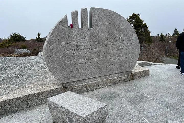 Steinernes Denkmal mit eingravierter Inschrift in einer Außenlandschaft.